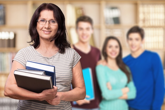 Зрелая улыбающаяся женщина с книгами, учителем и студентами