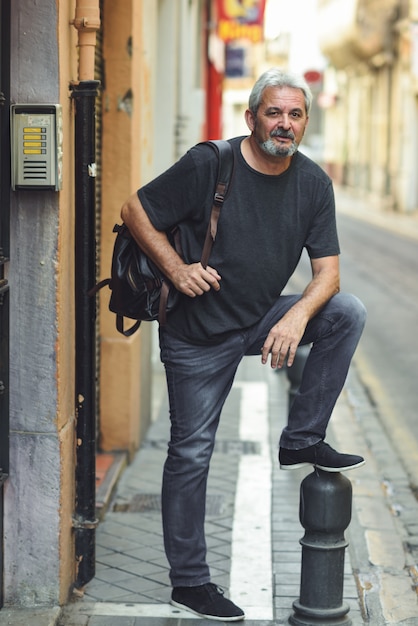 Free photo mature tourist man with travel backpack in urban background.