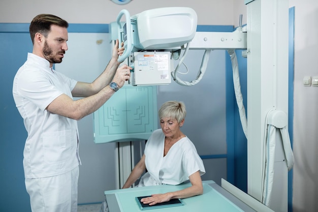 Бесплатное фото Зрелая женщина и медицинский техник во время рентгеновского сканирования рук в больнице xaxa