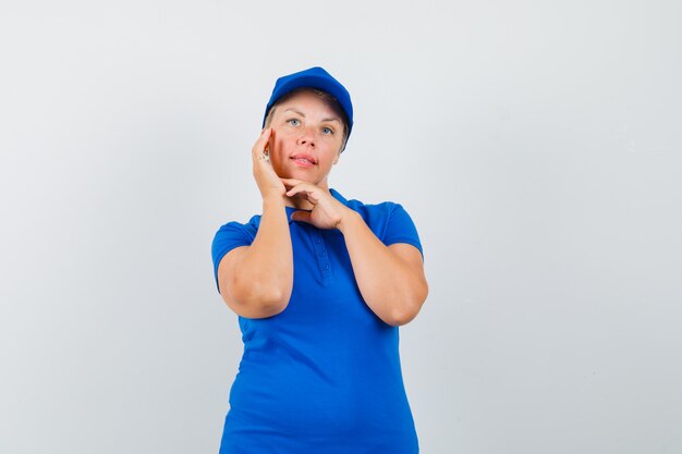 Mature woman checking her face skin in blue t-shirt
