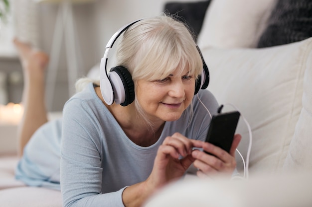 Зрелая женщина, выбирающая музыку на смартфоне