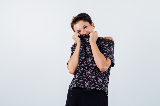 Mature woman covering mouth with blouse in blouse and looking cute. front view.