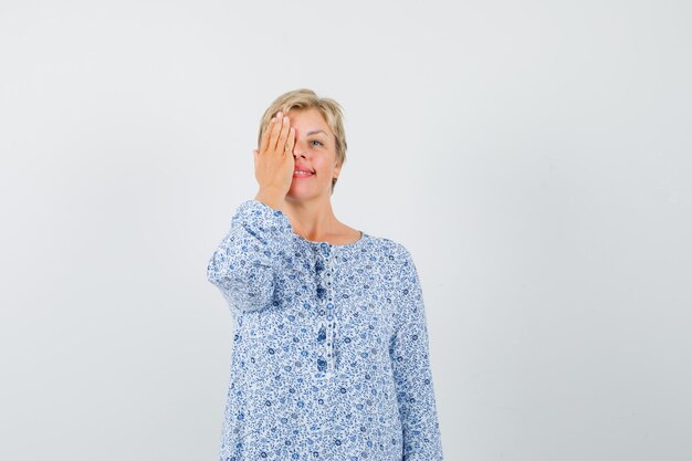 Mature woman in dress covering one eye with hand