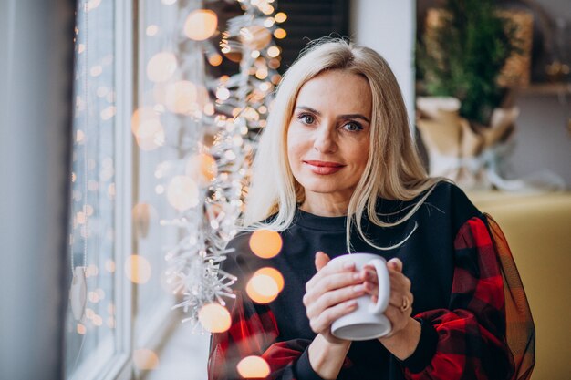 窓際でコーヒーを飲む熟女