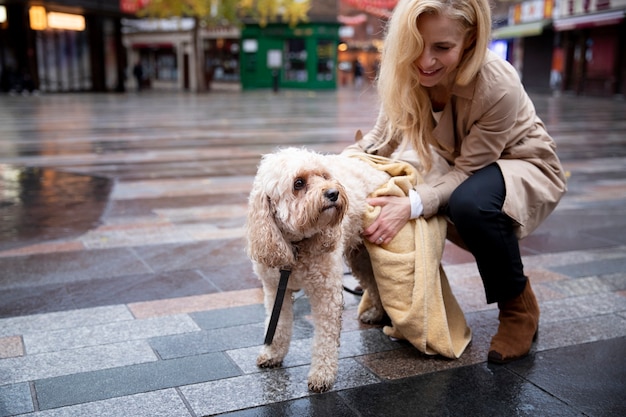 Mature woman drying her dog during their walk while it rains