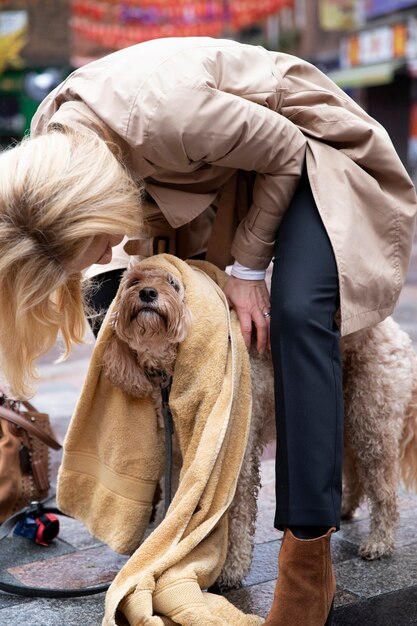 Mature woman drying her dog during their walk while it rains