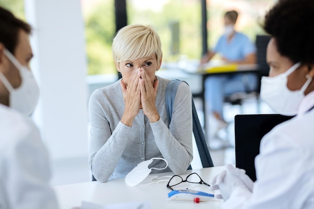 Donna matura che si sente preoccupata mentre ha appuntamento presso l'ufficio del medico durante l'epidemia di coronavirus