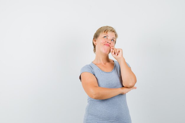 Mature woman looking up in grey t-shirt and looking hesitant