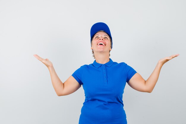 Mature woman looking up, spreading arms in t-shirt and looking happy