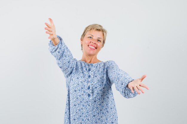 Mature woman opening arms for hug in shirt and looking happy.