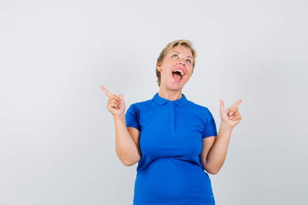 Mature woman pointing away in blue t-shirt and looking happy