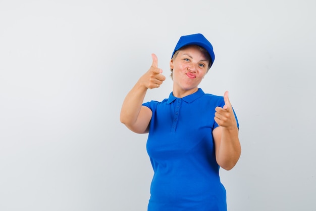 Mature woman pointing at front in blue t-shirt and looking confident.