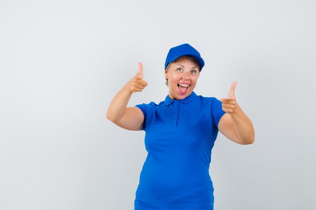 Mature woman pointing at front in blue t-shirt and looking frisky