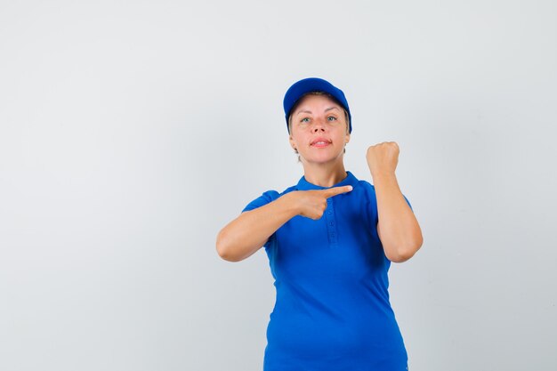 Mature woman pointing at her raised fist in t-shirt and looking confident.