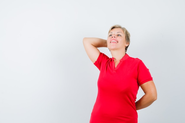 Mature woman posing while thinking in red t-shirt and looking relaxed.