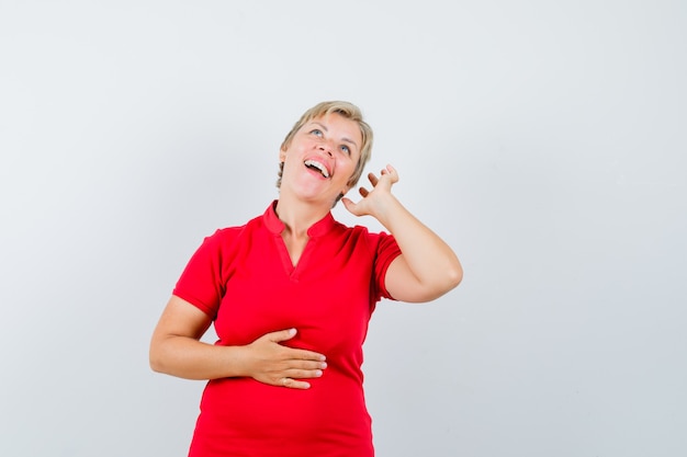 Mature woman pretending to enjoy music with headphones in red t-shirt