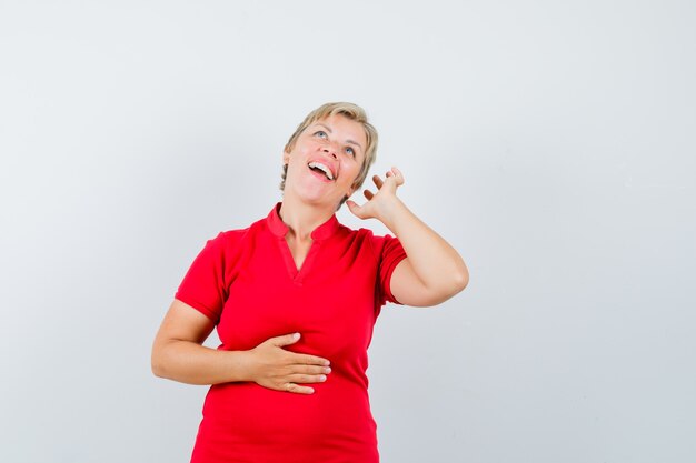 Mature woman pretending to enjoy music with headphones in red t-shirt