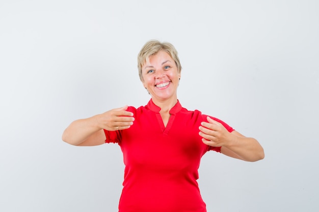 Mature woman pretending to hold something in red t-shirt and looking cheerful