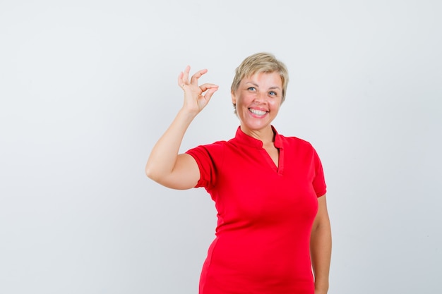 Mature woman in red t-shirt showing ok gesture and looking cheerful