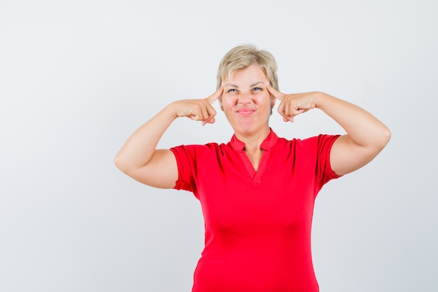 Mature woman in red t-shirt suffering from headache and looking uncomfortable