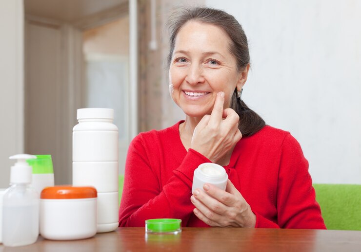 mature woman in red uses cosmetic cream