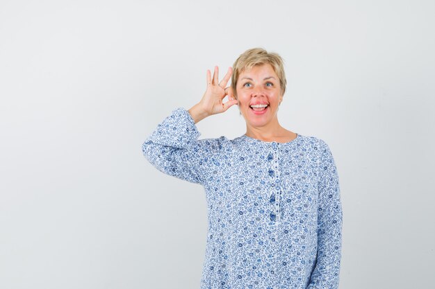 Free photo mature woman showing ok gesture in dress and looking jolly.