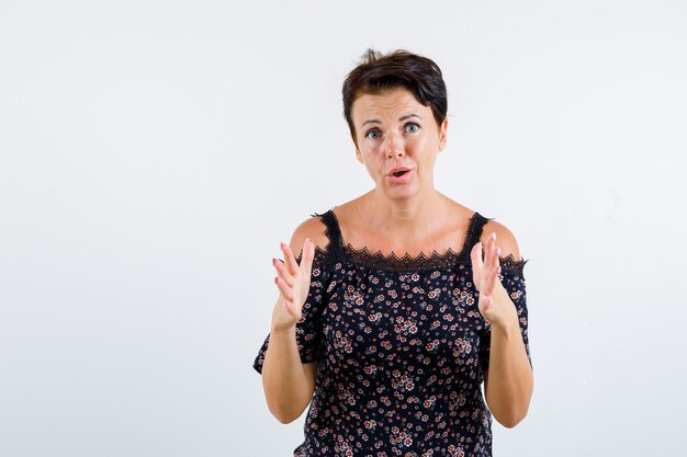 Mature woman showing scales in floral blouse, black skirt and looking excited. front view.