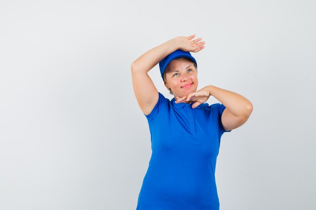 Mature woman showing traditional dance gesture in blue t-shirt and looking cute