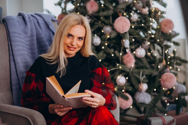 Donna matura che si siede nella sedia dall'albero di natale