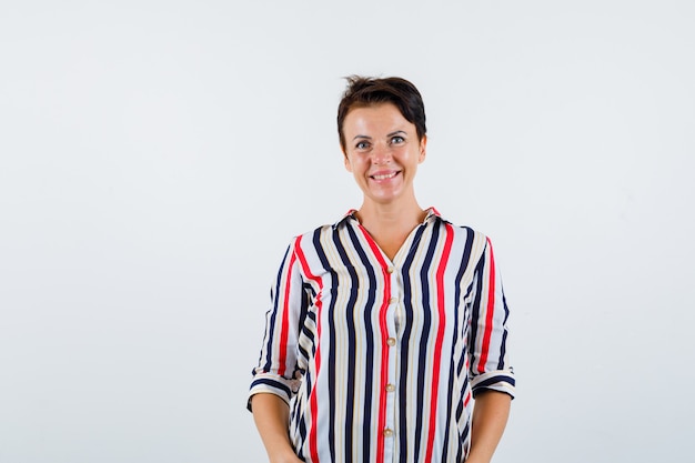 Mature woman in striped blouse standing straight and posing at camera and looking confident , front view.