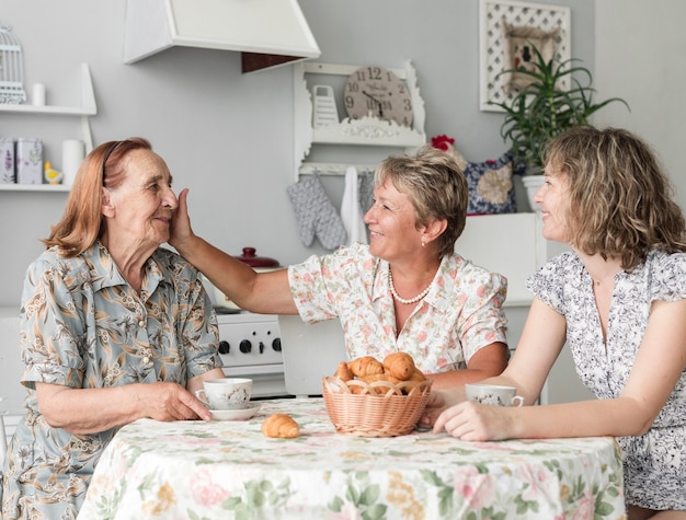 Donna matura che segna sua madre senior mentre mangiando prima colazione