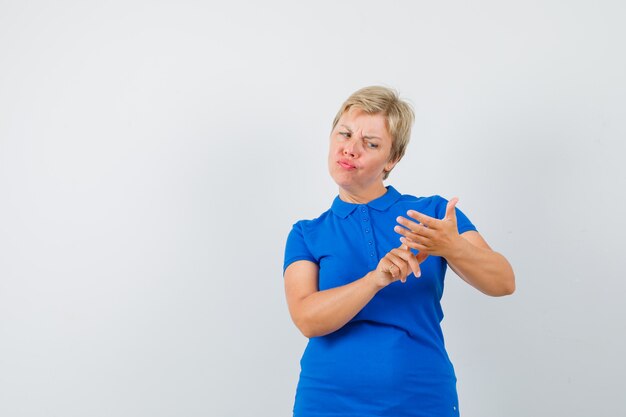 Зрелая женщина в футболке жестикулирует, как делает макияж