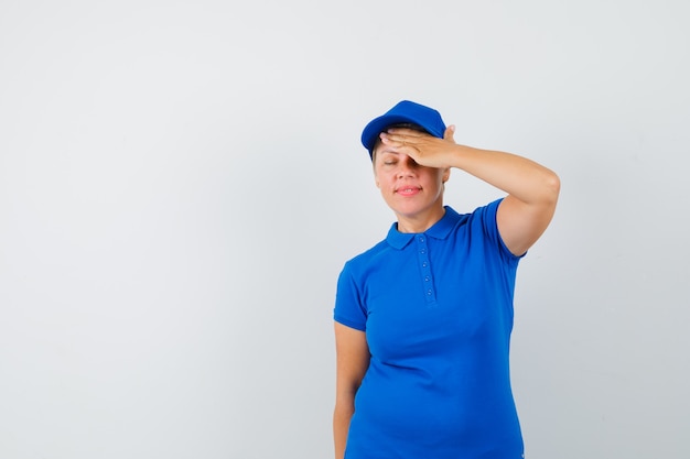 Mature woman in t-shirt holding hand over forehead