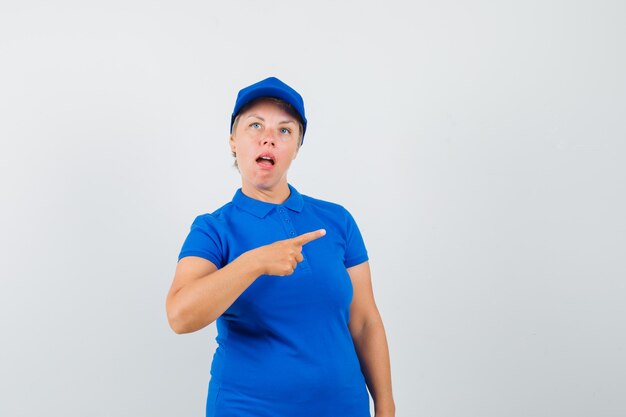 Mature woman in t-shirt pointing to the side and looking confused