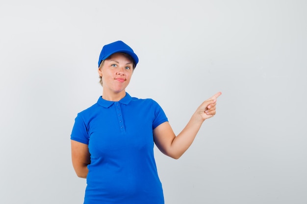 Mature woman in t-shirt pointing at upper right corner and looking confident