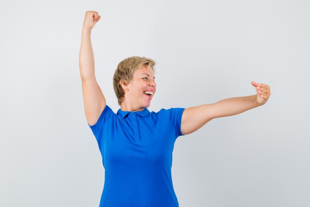 Mature woman in t-shirt pretending to hold something and looking happy