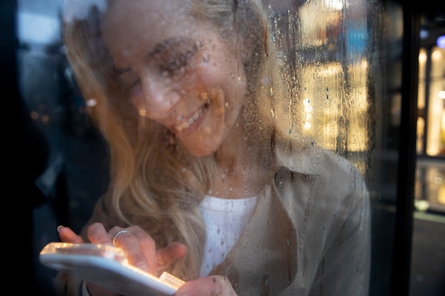 Foto gratuita donna matura che manda un sms al telefono mentre piove