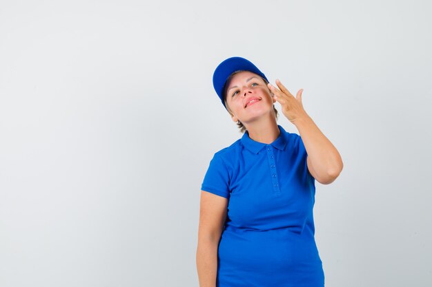 Mature woman touching her face skin on cheek in t-shirt and looking elegant