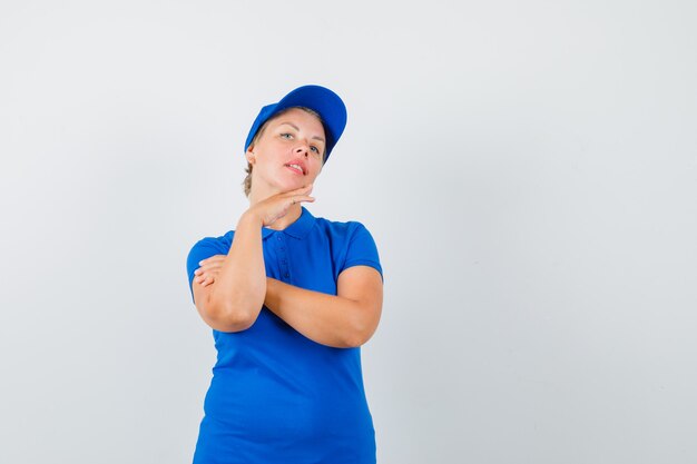 Mature woman touching her skin on chin in blue t-shirt and looking cute