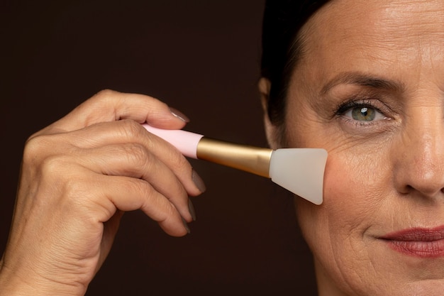 Mature woman using rose quartz face brush