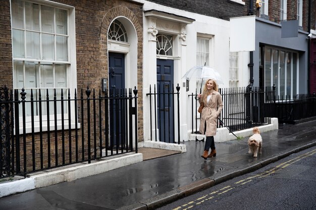 雨が降っている間、街の通りで彼女の犬を歩く成熟した女性
