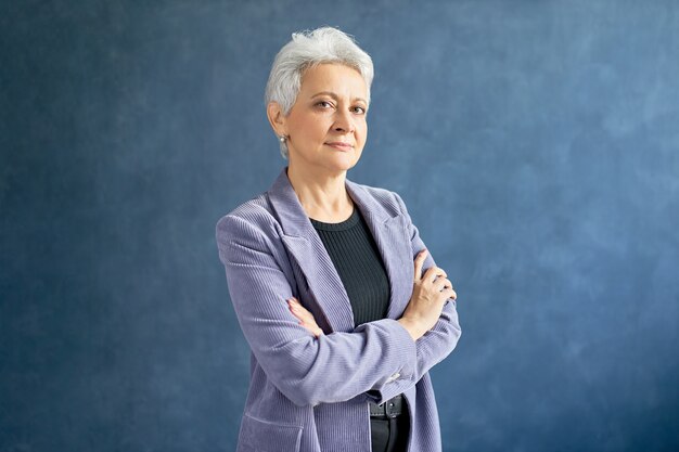 Mature woman with grey hair posing with violet jacket