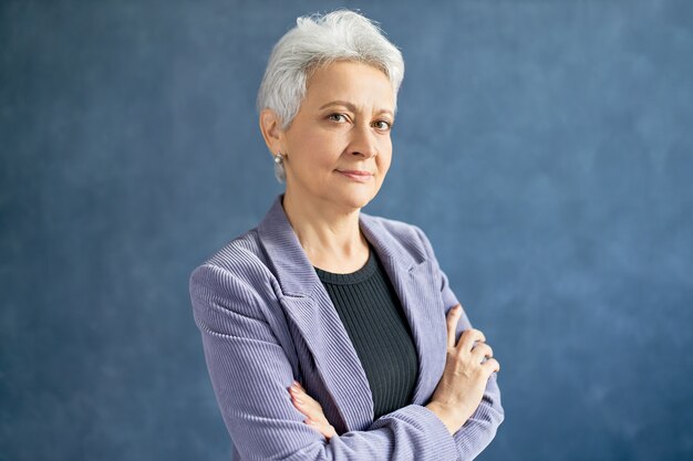 Mature woman with grey hair posing with violet jacket