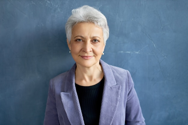 Mature woman with grey hair posing with violet jacket