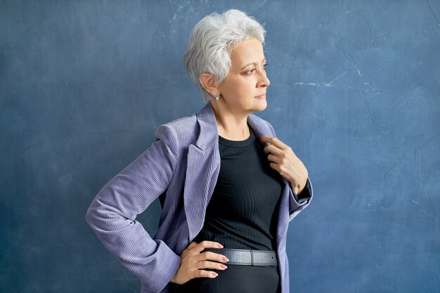 Mature woman with grey hair posing with violet jacket