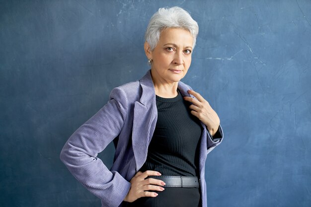 Mature woman with grey hair posing with violet jacket