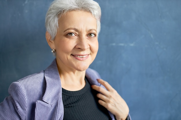 Mature woman with grey hair posing with violet jacket