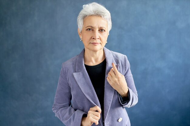 Mature woman with grey hair posing with violet jacket