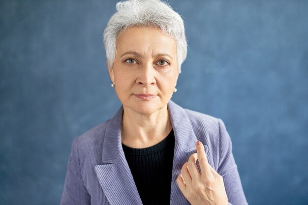 Mature woman with grey hair posing with violet jacket