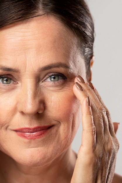 Free photo mature woman with make-up on posing with hand on face